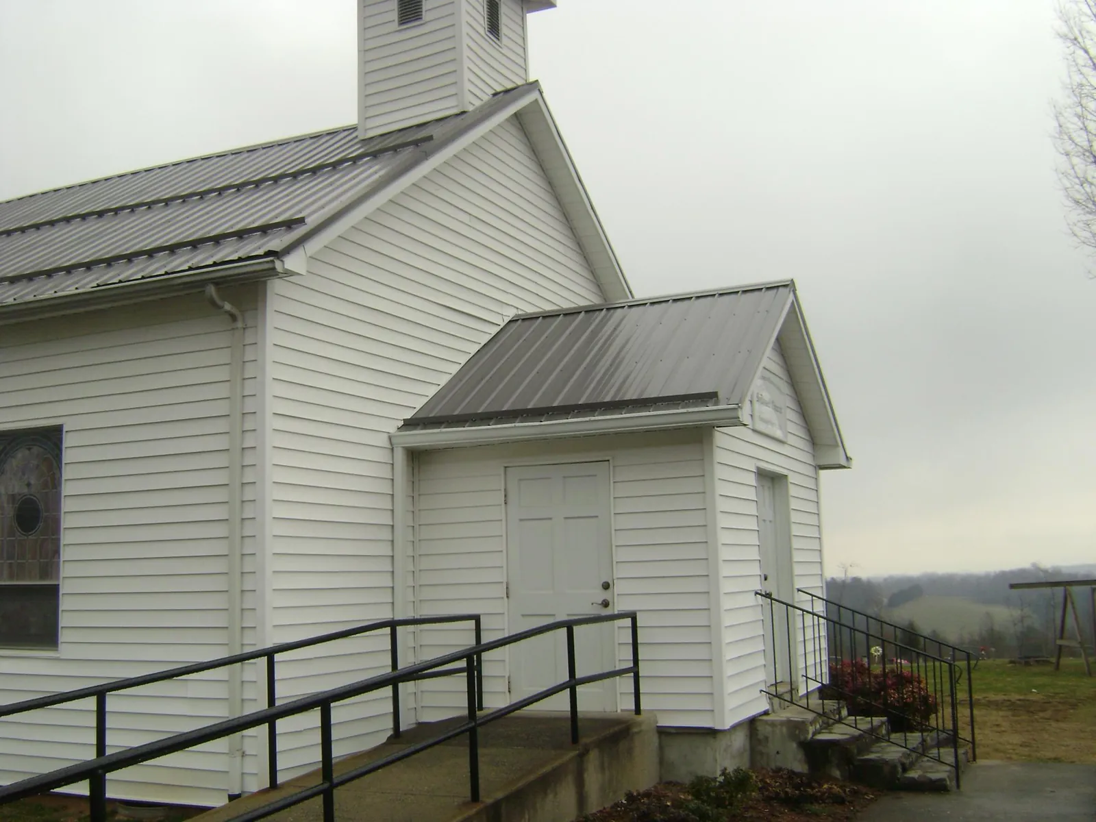 Gray metal roof on a white clapboard church with a steeple in Fayetteville